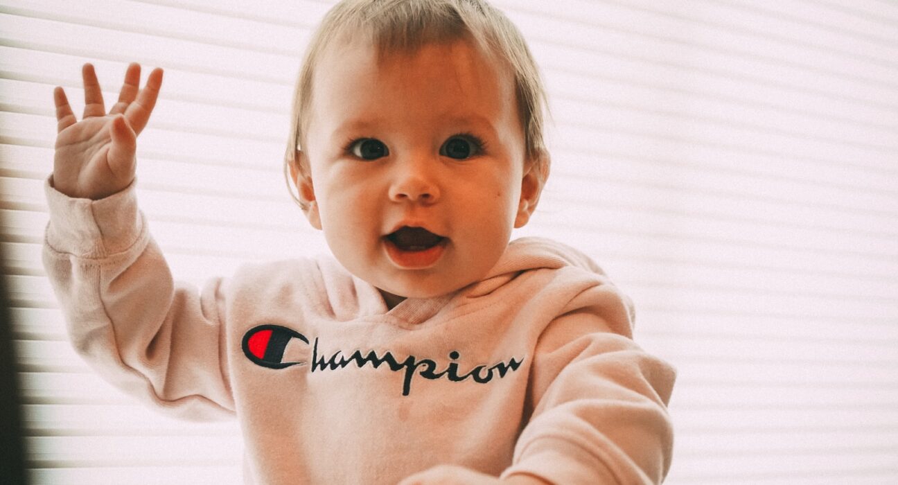 smiling toddler wearing white Champion pullover hoodie