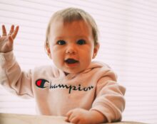smiling toddler wearing white Champion pullover hoodie