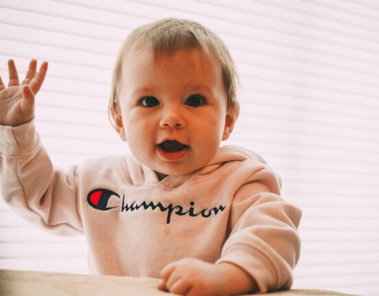 smiling toddler wearing white Champion pullover hoodie
