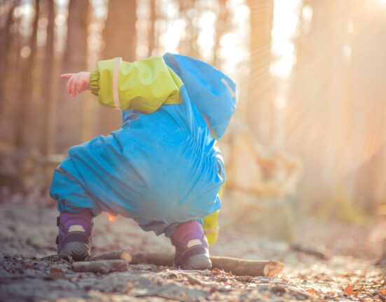 toddler picking up tree branch