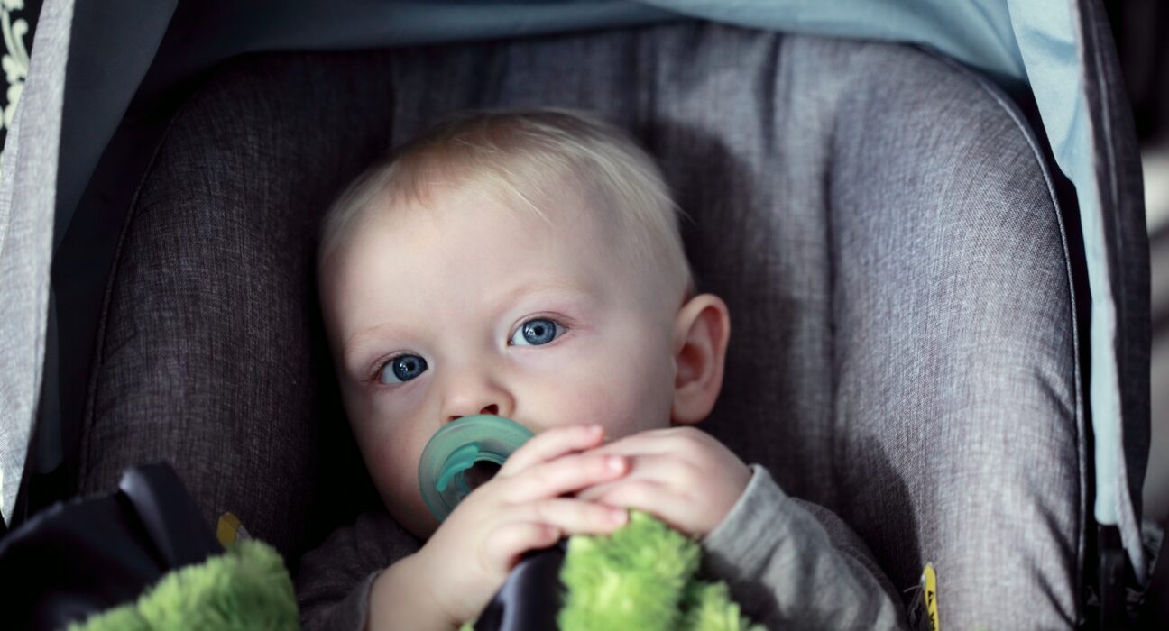 baby on gray stroller