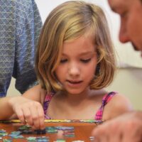 girl in blue and white polka dot tank top playing on brown wooden table