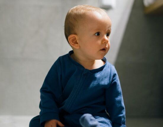baby in blue long sleeve shirt and blue denim jeans sitting on floor