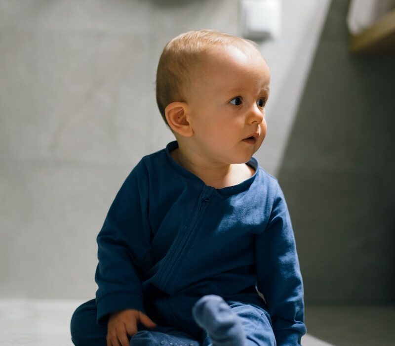 baby in blue long sleeve shirt and blue denim jeans sitting on floor