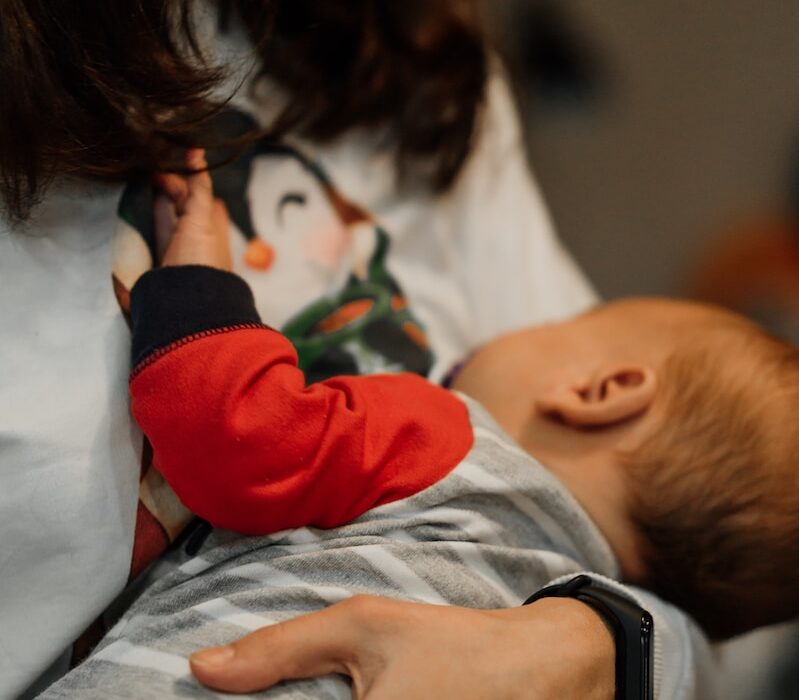 woman in white long sleeve shirt carrying baby in red and white long sleeve shirt